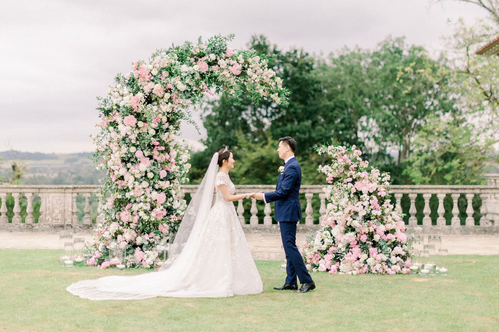 A Chinese bride and groom outside at Cliveden House getting married in front of a flower arch