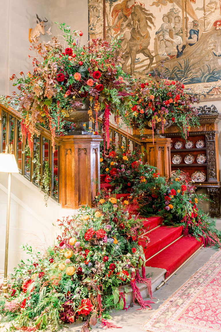 huge floral urns and cascading blooms falling down the carpeted steps of the grand staircase inside the castle