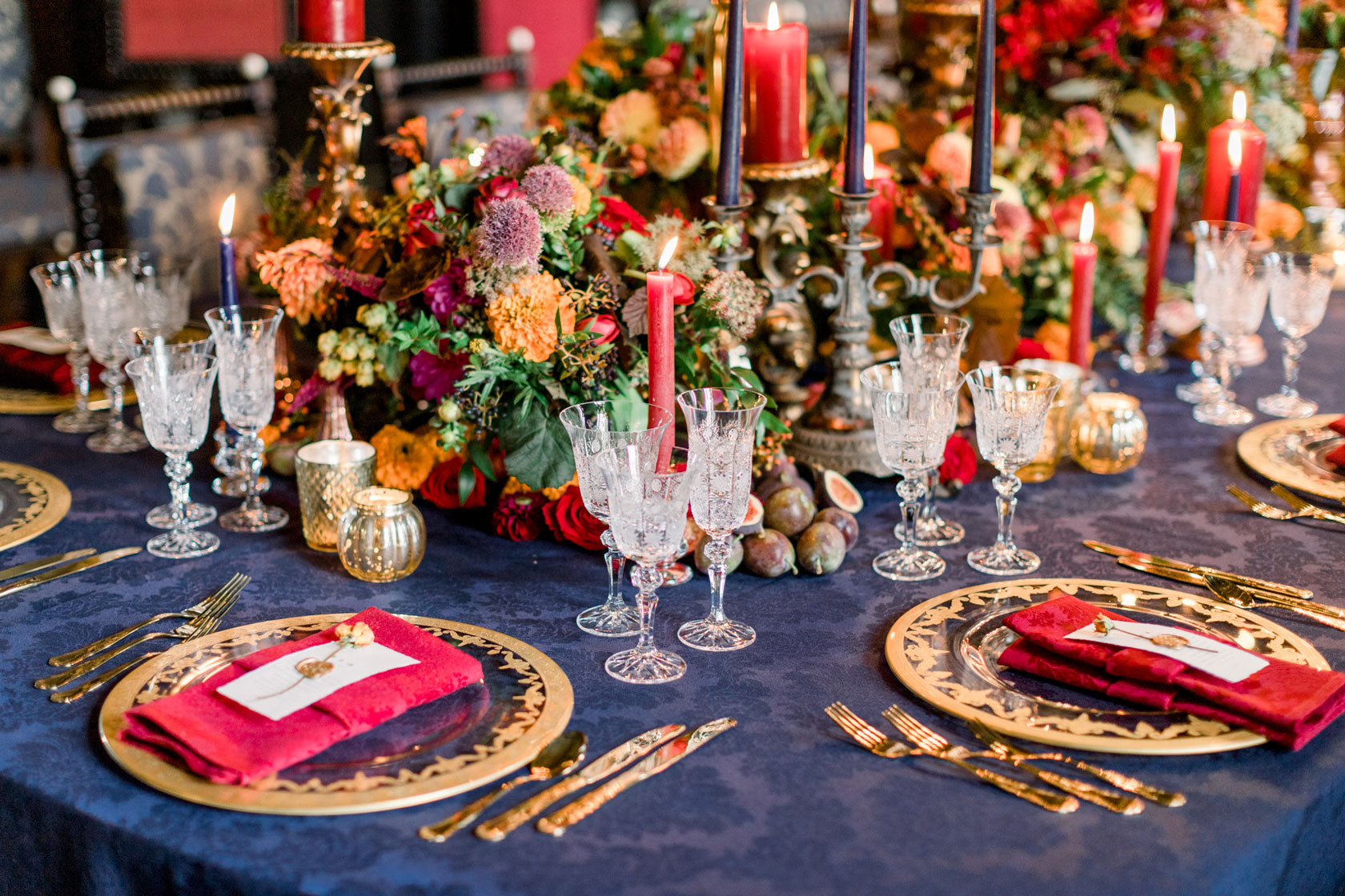navy linen, gold charger plates and cutlery, red napkins and delicate crystal glasses