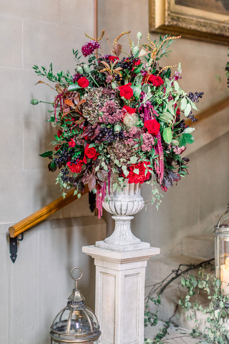 a white stone plynth with huge urns of red and green flowers