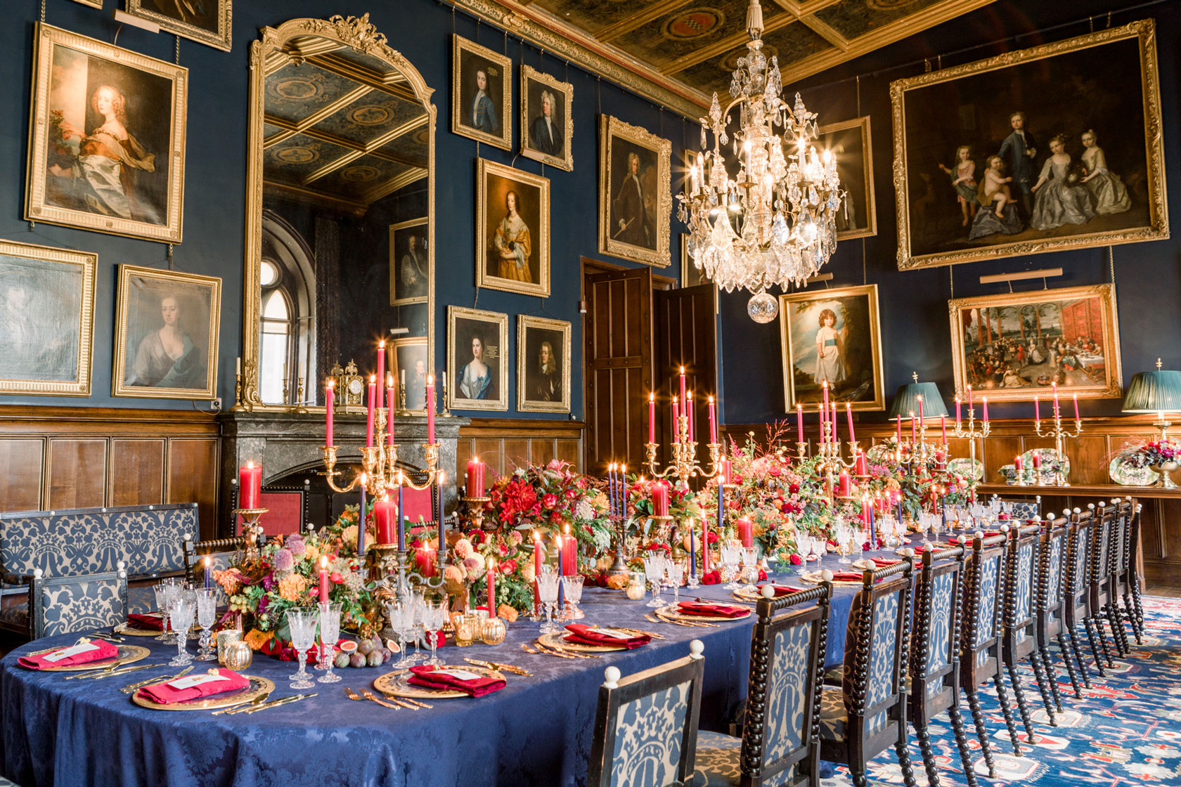 navy and gold regal inspired castle wedding breakfast banquet with hundreds of candles, gold chalices of flowers inside a castle