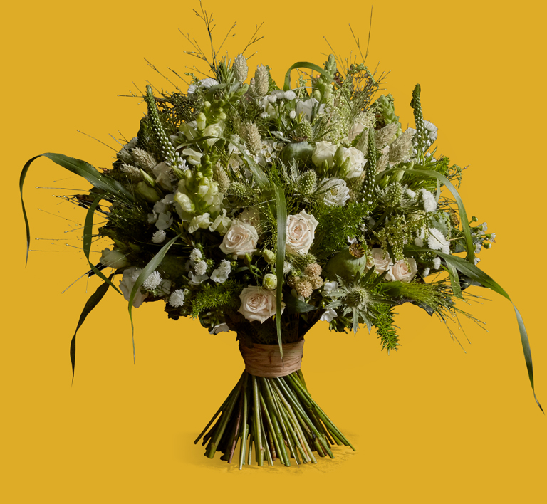 A white bouquet with white roses, asters, lisianthus, eryngium, phlox and wheat mixed with textured foliage and grasses